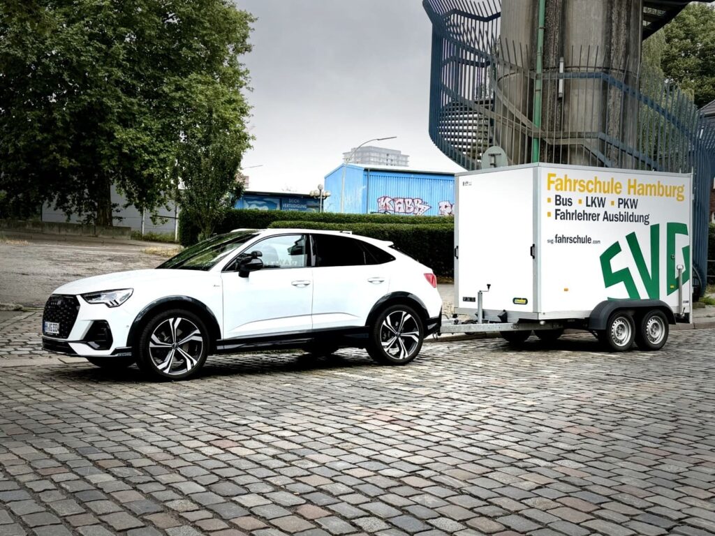 Weisser Audi SUV mit Fahrschule Hamburg Anhaenger auf Kopfsteinpflaster