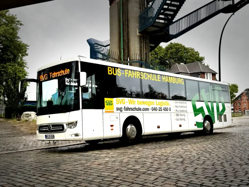 Weisser SVG Fahrschulbus aus Hamburg mit gruener Beschriftung auf Kopfsteinpflaster
